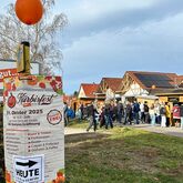 Plakat zum Kürbisfest 2025 mit Programmübersicht vor dem Marktzentrum Ranis, im Hintergrund zahlreiche Besucher auf dem Festgelände.