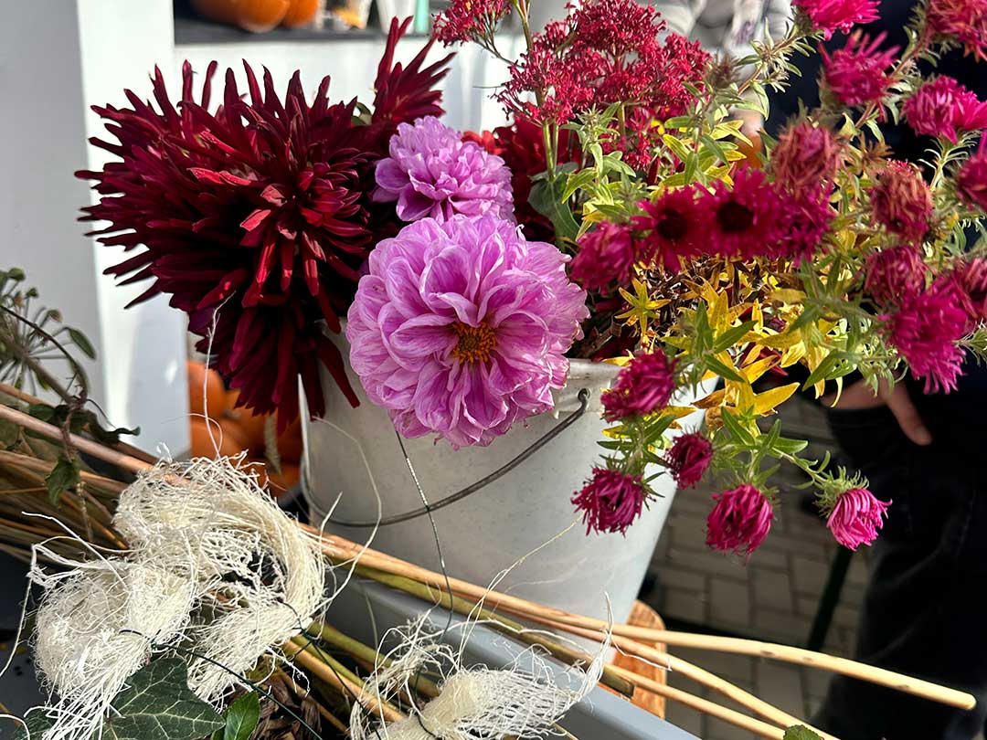 Herbstliche Blumenarrangements mit bunten Dahlien und Astern in einem Eimer beim Kürbisfest am Marktzentrum Ranis.
