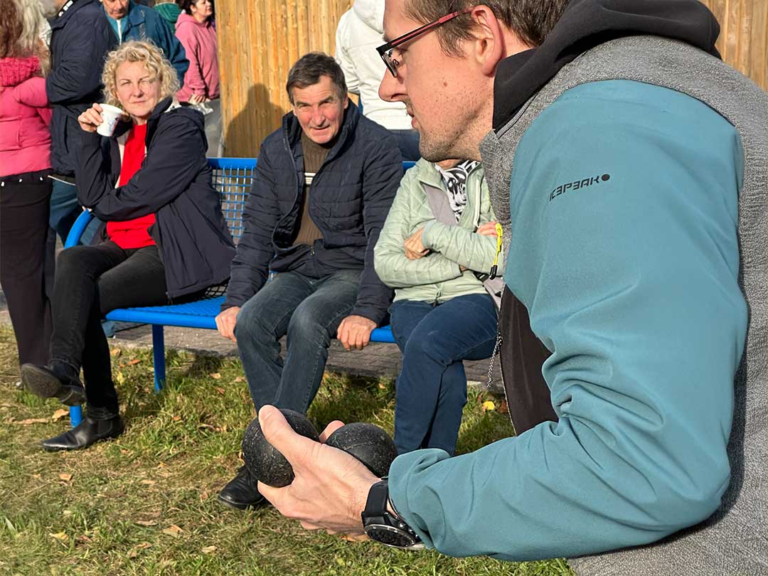 Teilnehmer beim Boule-Turnier am Marktzentrum Ranis konzentriert sich auf seinen Wurf, während Zuschauer das Spiel gespannt verfolgen.